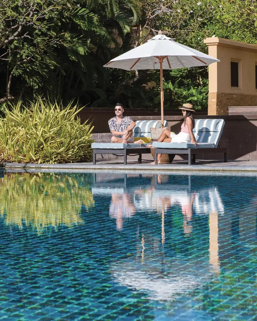 Poolside loungers under a parasol, representational image